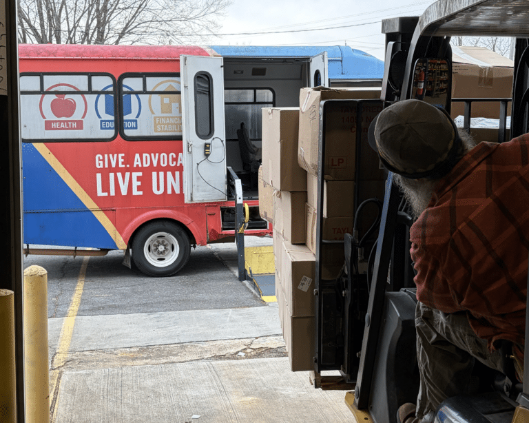 A pallet of donations being loaded onto a bus.