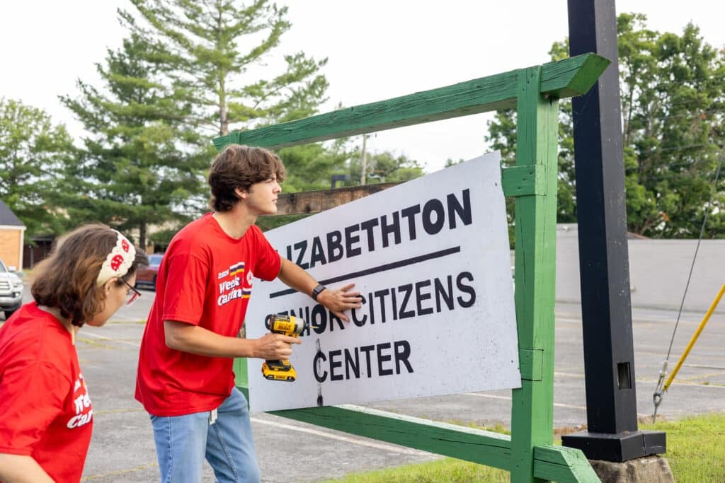 Volunteers replacing a sign at a nonprofit.