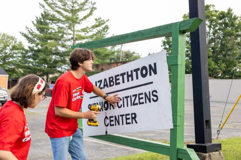 Volunteers replacing a sign at a nonprofit.